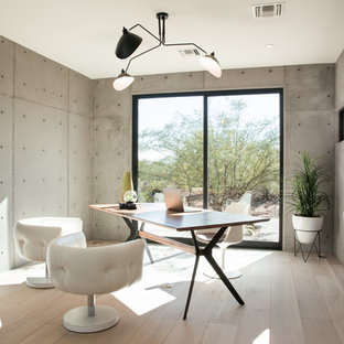Photo of a medium sized modern study in Phoenix with light hardwood flooring, a two-sided fireplace, a concrete fireplace surround and a freestanding desk.