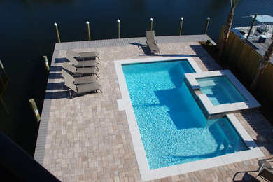 Inspiration for a large traditional backyard rectangular lap pool in Miami with a hot tub and natural stone pavers.