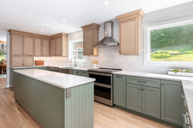Example of a mid-sized classic galley light wood floor and beige floor kitchen design in Other with a farmhouse sink, recessed-panel cabinets, green cabinets, quartzite countertops, white backsplash, subway tile backsplash, stainless steel appliances, an island and white countertops