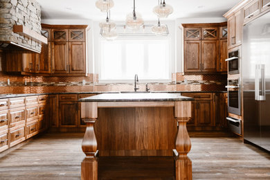 Design ideas for a large transitional kitchen in Calgary with raised-panel cabinets, dark wood cabinets, granite benchtops, metal splashback, stainless steel appliances, dark hardwood floors, with island, brown floor and black benchtop.