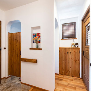 他の地域の中サイズの片開きドアカントリー風おしゃれな玄関ホール (白い壁、濃色無垢フローリング、木目調のドア、茶色い床) の写真