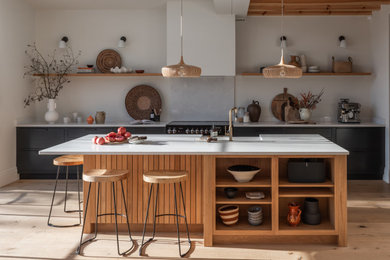 Inspiration for a large contemporary single-wall open plan kitchen in Other with flat-panel cabinets, black cabinets, quartz worktops, light hardwood flooring, an island, white worktops, a wood ceiling and feature lighting.
