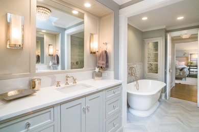 This is an example of a large transitional master bathroom in Chicago with furniture-like cabinets, white cabinets, a freestanding tub, an open shower, a two-piece toilet, beige tile, gray tile, porcelain tile, grey walls, porcelain floors, an undermount sink, engineered quartz benchtops, grey floor, an open shower and white benchtops.