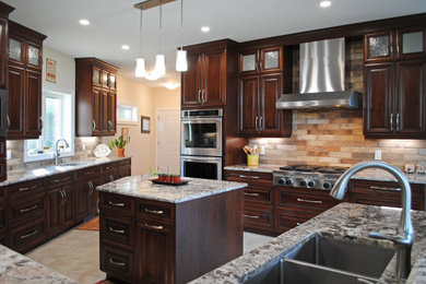 Kitchen pantry - large traditional ceramic tile and brown floor kitchen pantry idea in Toronto with a double-bowl sink, raised-panel cabinets, medium tone wood cabinets, granite countertops, brown backsplash, stone tile backsplash, stainless steel appliances, an island and brown countertops