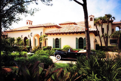 Example of a large tuscan beige two-story stucco house exterior design in Miami with a hip roof and a tile roof