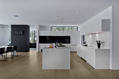 Example of a huge trendy l-shaped concrete floor open concept kitchen design in Minneapolis with an undermount sink, flat-panel cabinets, white cabinets, quartz countertops, white backsplash, quartz backsplash, an island and white countertops