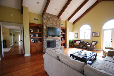 Large minimalist enclosed medium tone wood floor and brown floor family room photo in San Diego with beige walls, a standard fireplace, a stone fireplace and a wall-mounted tv