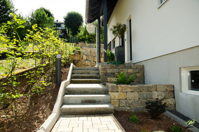 Mittelgroßer Hanggarten im Sommer mit Gehweg und Natursteinplatten in Frankfurt am Main
