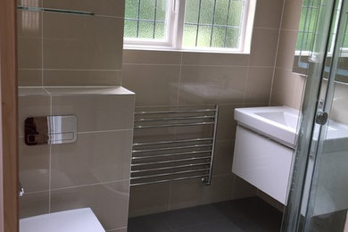 Design ideas for a modern master bathroom in Essex with a wall-mount sink, a corner shower, a wall-mount toilet, beige tile, porcelain tile and porcelain floors.