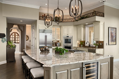 Eat-in kitchen - large traditional l-shaped dark wood floor and brown floor eat-in kitchen idea in Denver with an undermount sink, shaker cabinets, beige cabinets, granite countertops, metallic backsplash, glass tile backsplash, stainless steel appliances, an island and multicolored countertops