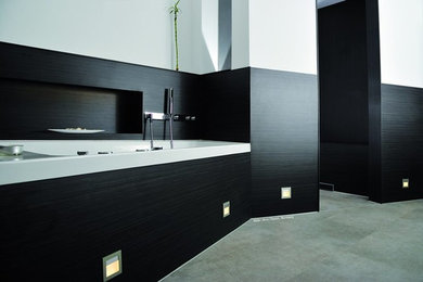 Modernes Badezimmer mit weißen Schränken, Eckdusche, schwarzer Wandfarbe, Aufsatzwaschbecken, grauem Boden und Falttür-Duschabtrennung in München
