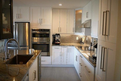 Example of a small trendy galley ceramic tile and gray floor open concept kitchen design in San Francisco with an undermount sink, shaker cabinets, white cabinets, granite countertops, brown backsplash, glass tile backsplash, stainless steel appliances and an island
