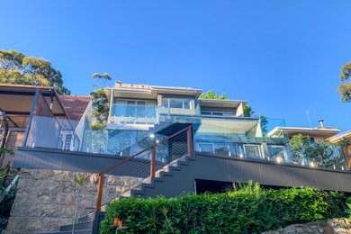Imagen de terraza planta baja minimalista grande sin cubierta en patio trasero con privacidad y barandilla de varios materiales