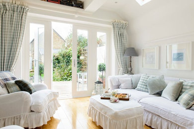 Small shabby-chic style living room in Kent with white walls, medium hardwood flooring and feature lighting.