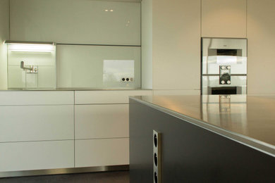 Idée de décoration pour une grande cuisine linéaire design avec des portes de placard blanches, un plan de travail en surface solide, sol en béton ciré et îlot.