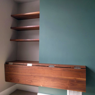 Small modern study in London with green walls, carpet, a built-in desk and beige floors.