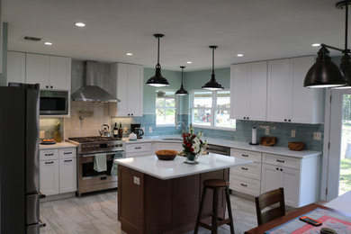 This is an example of a mid-sized country eat-in kitchen in Austin with a farmhouse sink, shaker cabinets, white cabinets, quartz benchtops, blue splashback, ceramic splashback, stainless steel appliances, ceramic floors, with island, grey floor and white benchtop.