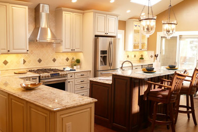 Inspiration for a mid-sized transitional l-shaped medium tone wood floor kitchen remodel in Denver with raised-panel cabinets, white cabinets, granite countertops, beige backsplash, ceramic backsplash, stainless steel appliances and an island