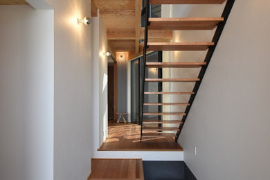 他の地域にあるコンテンポラリースタイルのおしゃれなスケルトン階段 (金属の手すり、壁紙) の写真