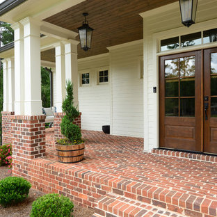 アトランタの両開きドアカントリー風おしゃれな玄関ドア (白い壁、木目調のドア、赤い床) の写真