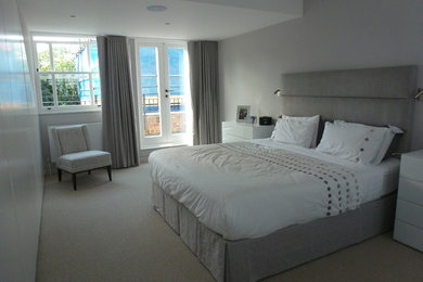 Mid-sized contemporary master bedroom in London with grey walls and carpet.