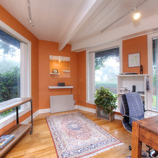 Idéer för att renovera ett litet eklektiskt hemmabibliotek, med orange väggar, ljust trägolv och ett fristående skrivbord