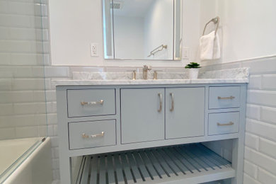 Example of a mid-sized trendy porcelain tile porcelain tile bathroom design in New York with marble countertops and a freestanding vanity
