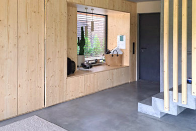 Geräumiger Moderner Eingang mit grauer Wandfarbe, Betonboden, Einzeltür, grauer Haustür, grauem Boden, Holzwänden und Treppe in Frankfurt am Main