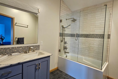 На фото: ванная комната среднего размера в стиле модернизм с плоскими фасадами, синими фасадами, угловой ванной, угловым душем, белой плиткой, керамической плиткой, белыми стенами, полом из керамогранита, врезной раковиной, стеклянной столешницей, синим полом, душем с распашными дверями, белой столешницей, тумбой под одну раковину, встроенной тумбой и сводчатым потолком с