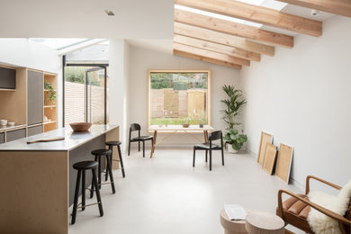 Photo of a medium sized modern cream and black single-wall open plan kitchen in London with flat-panel cabinets, black cabinets, stainless steel worktops, concrete flooring, an island, grey floors and exposed beams.