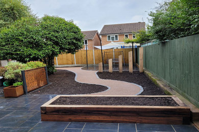 Photo of a medium sized modern back garden for spring in Sussex with a garden path, natural stone paving and a wood fence.