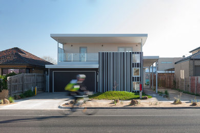 This is an example of a mid-sized contemporary two-storey beige house exterior in Melbourne with metal siding, a flat roof and a metal roof.