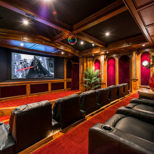 Photo of an expansive traditional enclosed home cinema in Atlanta with red walls, carpet, a projector screen and red floors.