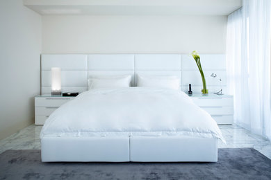 This is an example of a contemporary bedroom in Miami with white walls, no fireplace and marble floors.