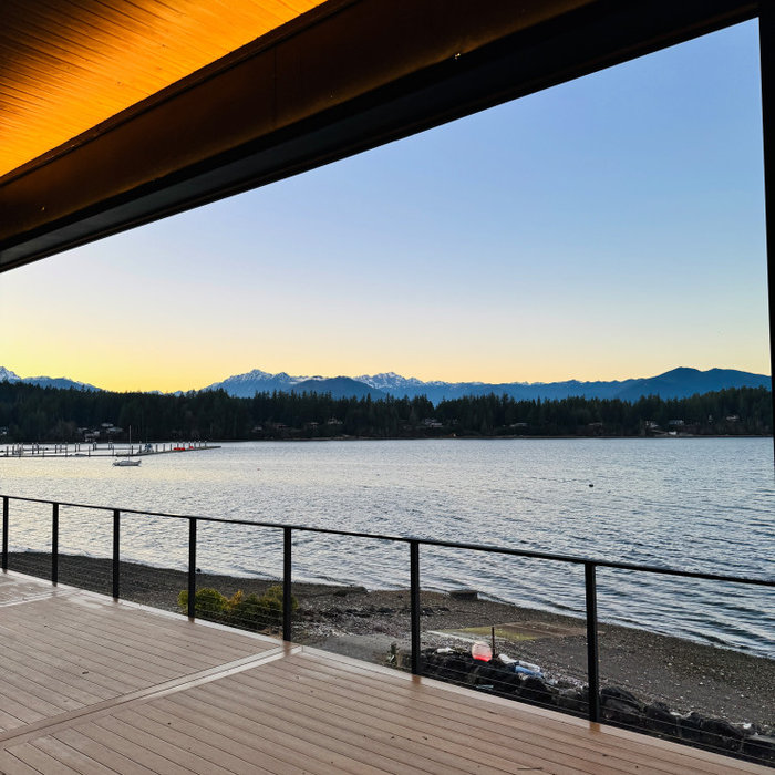 This waterfront deck highlights how thoughtful lighting design transforms an outdoor living space. Warm uplighting casts a soft glow across the cedar soffit, creating enough illumination for evening g