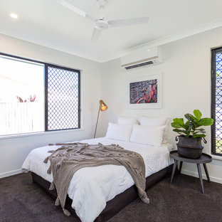 This is an example of a beach style guest bedroom in Other with grey walls, carpet and brown floor.
