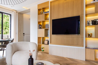 Réalisation d'un salon design ouvert avec un mur blanc, un sol en bois brun et un téléviseur fixé au mur.