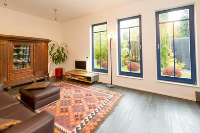 Großes, Offenes Modernes Wohnzimmer ohne Kamin mit weißer Wandfarbe, dunklem Holzboden, Multimediawand und braunem Boden in Frankfurt am Main