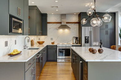 Inspiration for a large modern l-shaped kitchen/diner in New York with a submerged sink, flat-panel cabinets, grey cabinets, engineered stone countertops, white splashback, engineered quartz splashback, stainless steel appliances, light hardwood flooring, an island, brown floors and white worktops.