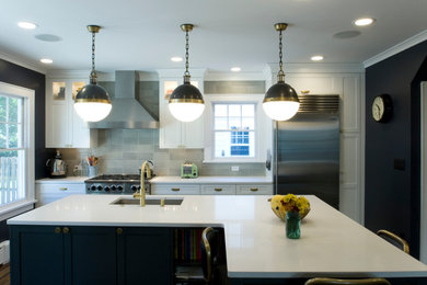 Transitional medium tone wood floor kitchen photo in New York with an undermount sink, recessed-panel cabinets, solid surface countertops, gray backsplash, ceramic backsplash, stainless steel appliances and an island