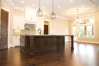 Mid-sized transitional l-shaped dark wood floor and brown floor eat-in kitchen photo in Houston with an undermount sink, recessed-panel cabinets, white cabinets, granite countertops and an island