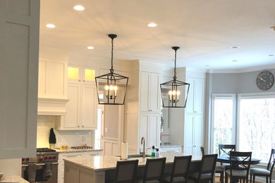 Design ideas for a large traditional l-shaped eat-in kitchen in Raleigh with a double-bowl sink, shaker cabinets, white cabinets, granite benchtops, white splashback, porcelain splashback, stainless steel appliances, medium hardwood floors, with island and brown floor.
