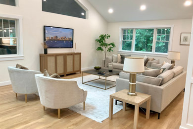 Family room - large transitional open concept light wood floor and vaulted ceiling family room idea in Boston with white walls and a wall-mounted tv