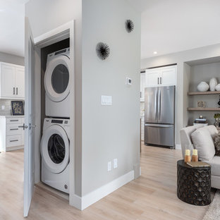 Inspiration for a small classic single-wall laundry cupboard in Vancouver with grey walls, laminate floors, a stacked washer and dryer and beige floors.