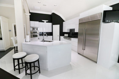 Large modern u-shaped eat-in kitchen in Houston with an undermount sink, flat-panel cabinets, white cabinets, quartz benchtops, black splashback, glass sheet splashback, stainless steel appliances, porcelain floors, with island, white floor and white benchtop.