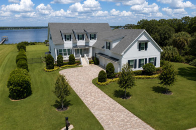 Large beach style two-story stucco exterior home photo in Tampa with a shingle roof