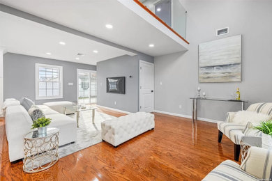 Example of a large trendy formal and open concept medium tone wood floor, brown floor, tray ceiling and shiplap wall living room design in New York with gray walls, a standard fireplace, a stone fireplace and a wall-mounted tv