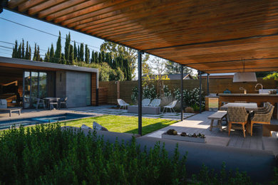 Пример оригинального дизайна: большой солнечный участок и сад на заднем дворе в стиле модернизм с хорошей освещенностью, мощением тротуарной плиткой и с деревянным забором