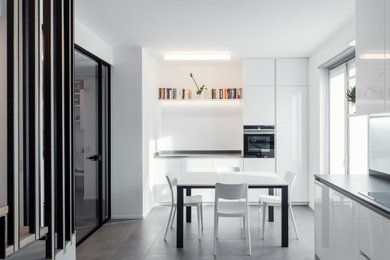 Contemporary l-shaped eat-in kitchen in Other with flat-panel cabinets, white cabinets, stainless steel appliances, no island, grey floor and grey benchtop.