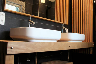 Cette photo montre une salle de bain moderne de taille moyenne avec un carrelage noir, des carreaux de céramique, un plan de toilette en bois et meuble double vasque.